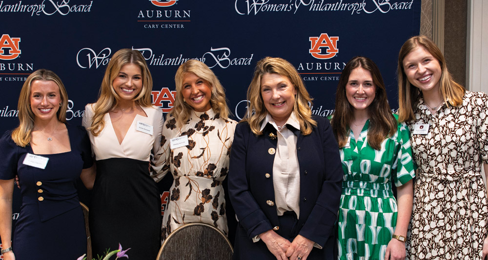 Six women pose for a group photo in front of a backdrop featuring the Auburn University and Women's Philanthropy Board logos.