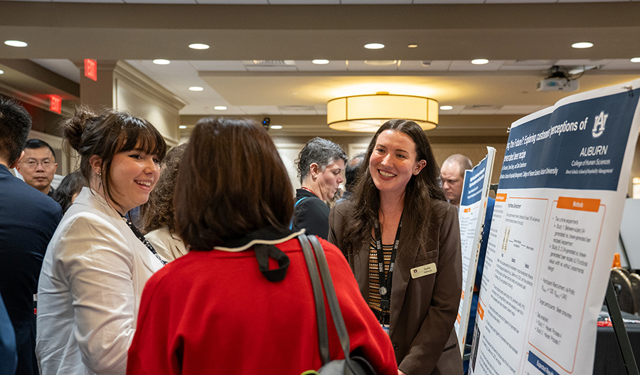 Student presenting a research poster about AI-generated recipes to engaged event attendees.