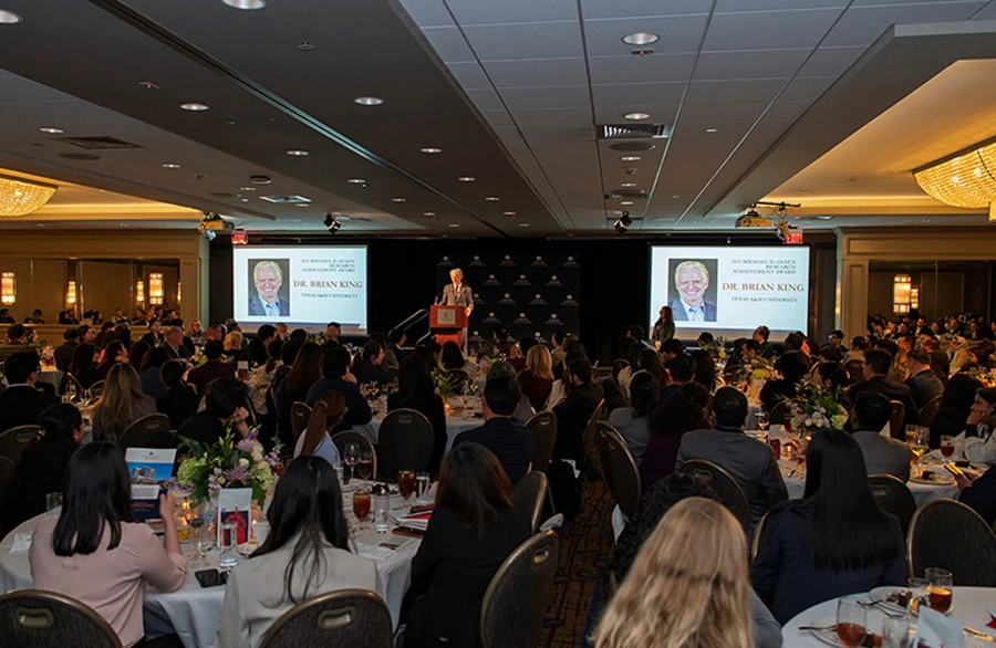 Large ballroom gala with guest speakers and screens honoring award recipient Dr. Brian King.