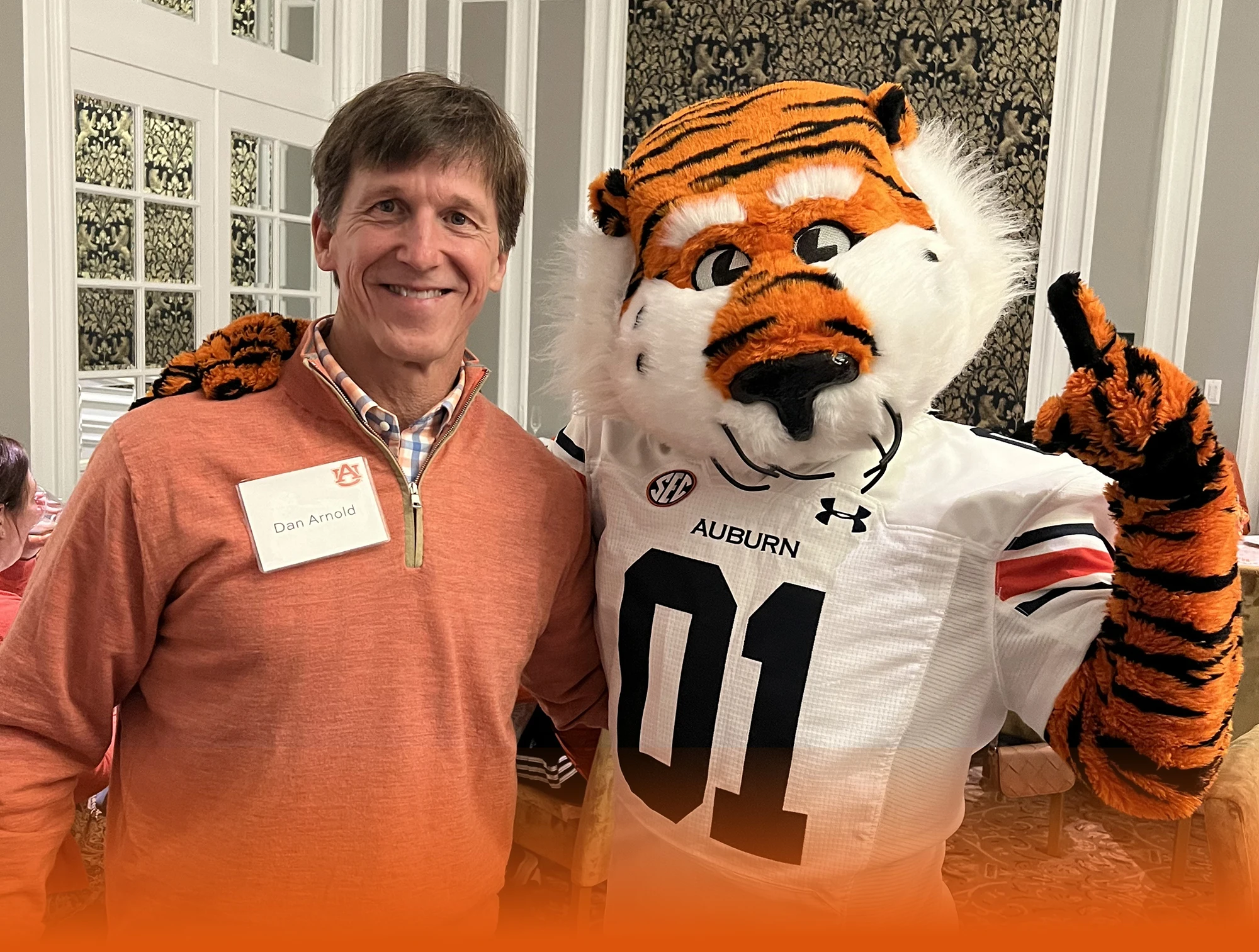 Dan Arnold, a smiling man in an orange quarter-zip pullover and a name tag with Aubie the Tiger, the Auburn University mascot
